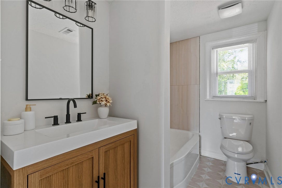 7406 Alycia Avenue, Henrico, VA 23228 Wood-finish vanity with white integrated sink, matte black faucet, and rectangular mirror