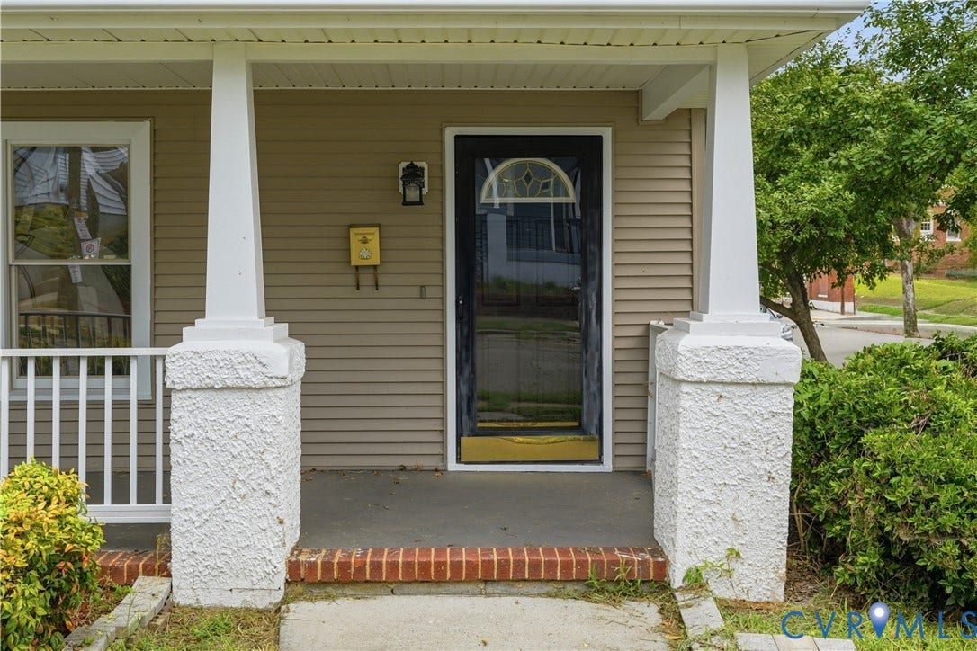 124 Lipscomb Street, Blackwell, Richmond, VA 23224 Covered front porch with white columns, horizontal siding, and a dark entry door with decorative glass
