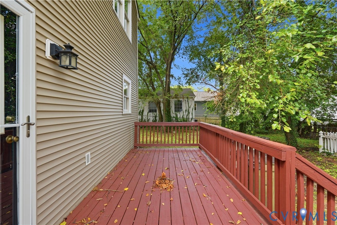 124 Lipscomb Street, Blackwell, Richmond, VA 23224 Hardscaped rear deck with red-toned wood flooring and railing, tan siding, and a decorative exterior light fixture