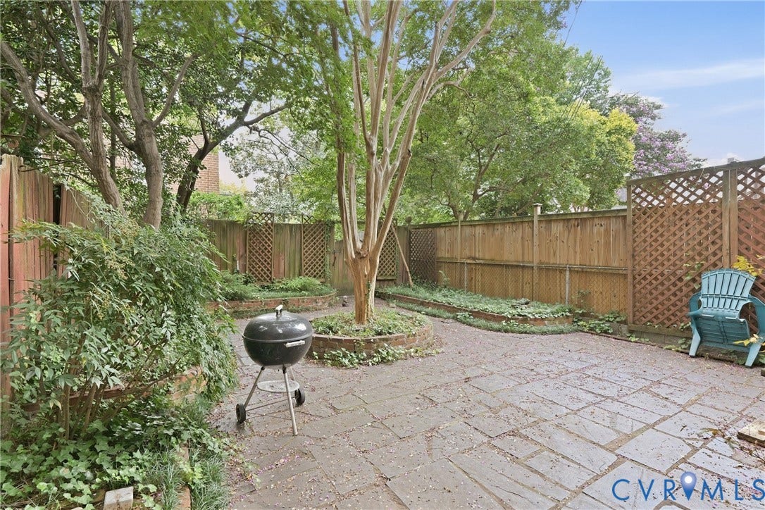 1505 Grove Avenue, Fan, Richmond, VA 23220 Private patio featuring a stone paver surface, raised planting beds, mature trees, and wood fencing with lattice accents