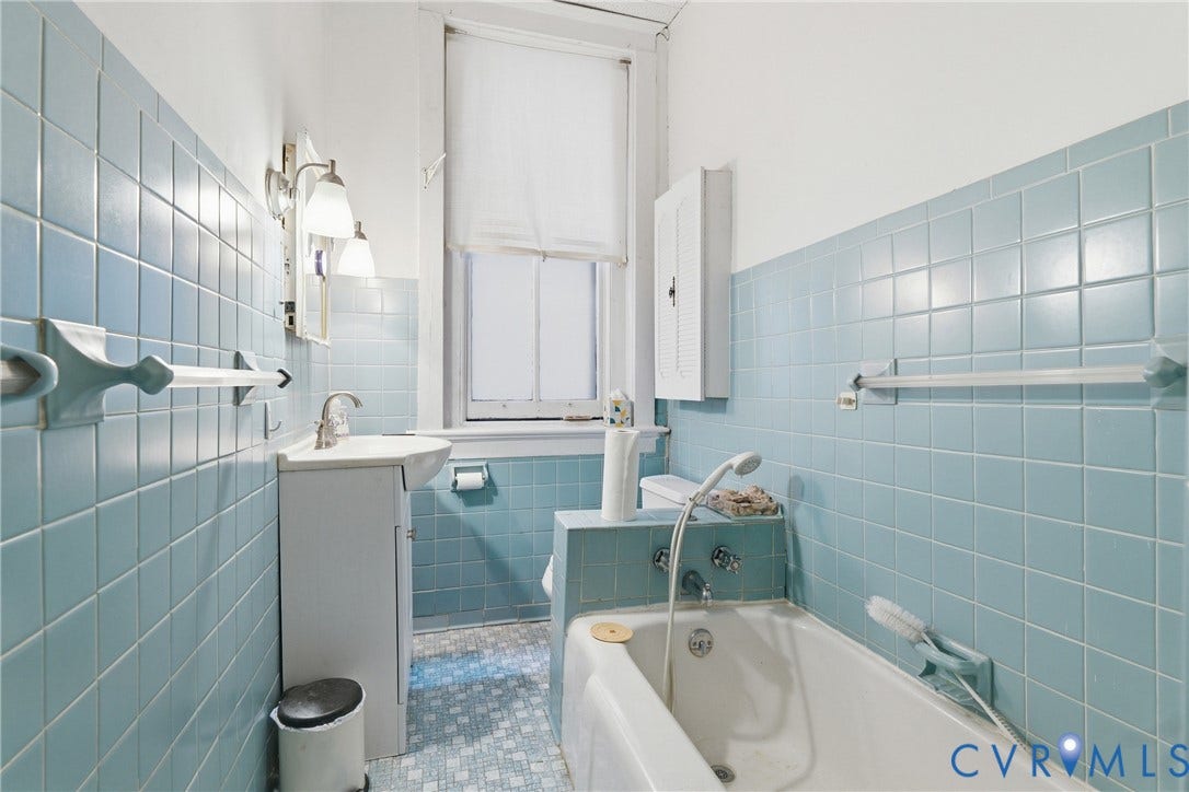 1505 Grove Avenue, Fan, Richmond, VA 23220 Bathroom featuring blue square wall tiles, a white vanity with an integrated sink, a built-in bathtub, and a window with a roller shade