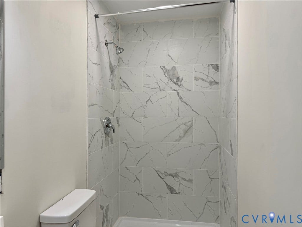 1605 Cartersville Road, Quiet, Goochland, VA 23063 Shower enclosure with white tile featuring gray veining, chrome showerhead, and matching chrome faucet