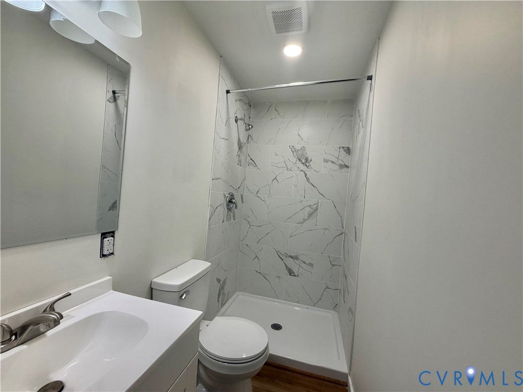 1605 Cartersville Road, Quiet, Goochland, VA 23063 Vanity with integrated sink, brushed nickel faucet, large wall mirror, walk-in shower with marble-style tile surround, and recessed lighting