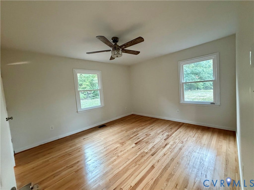 1605 Cartersville Road, Quiet, Goochland, VA 23063 Hardwood flooring with a natural finish, two double-hung windows, and a ceiling fan with integrated lighting