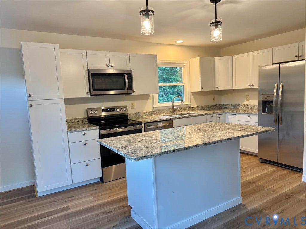 1605 Cartersville Road, Quiet, Goochland, VA 23063 Kitchen featuring white shaker cabinetry, stainless steel appliances, speckled stone countertops, a central island, and wood-finish flooring