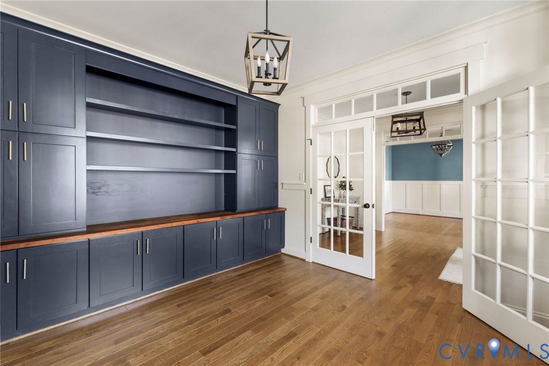 Built-in cabinetry with wood-finish countertop, wood-finish flooring, glass-paneled double doors, and a decorative light fixture
