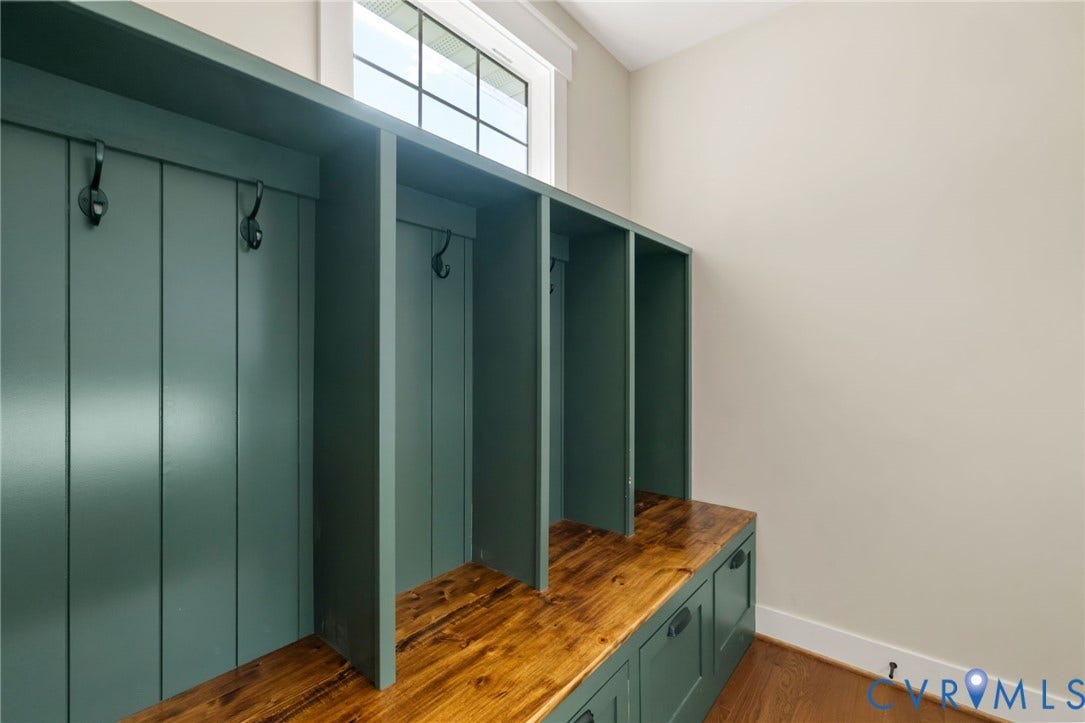 Built-in storage bench with wood-finish top, integrated cabinetry, and individual cubbies with coat hooks