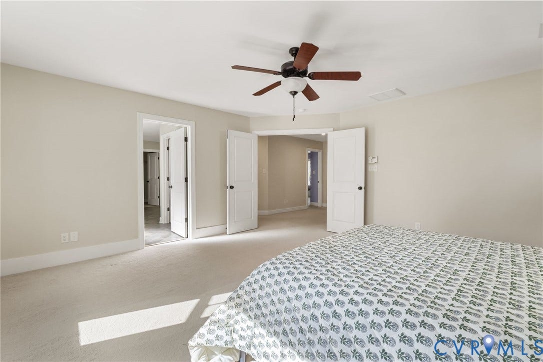 Neutral wall color, ceiling fan with wood-finish blades, and carpeted flooring