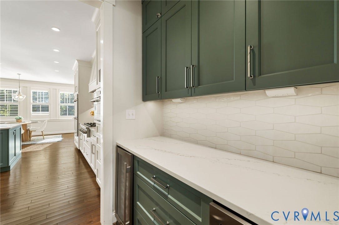 Custom cabinetry with integrated hardware, solid surface countertops, patterned tile backsplash, wood-finish flooring, and built-in appliances