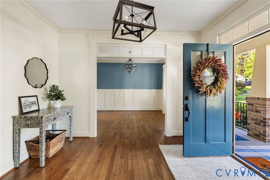Hardwood flooring, wood trim detailing, transom window above doorway, decorative light fixture, front entry door with glass panels