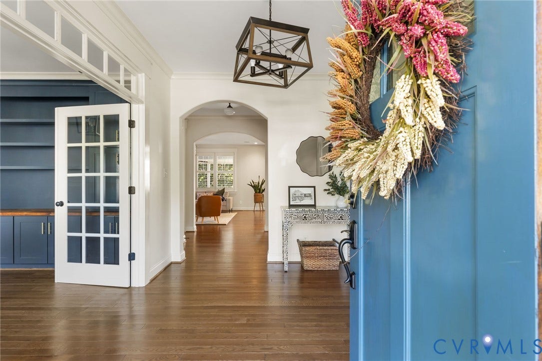 Hardwood flooring throughout, arched doorway, French doors with transom, built-in cabinetry with wood-finish countertop, and a decorative overhead light fixture