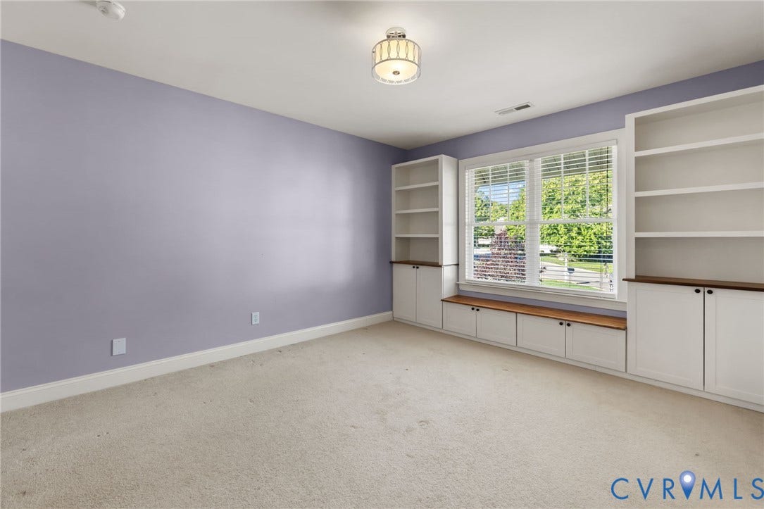 Built-in shelving flanking a large window with blinds, integrated window bench, and lower cabinetry with wood-finish tops