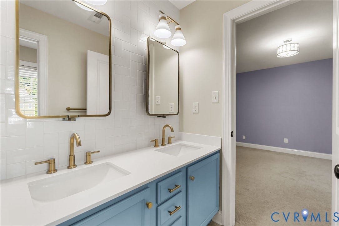 Dual vanity with undermount sinks, gold-finish hardware, and a white subway tile backsplash