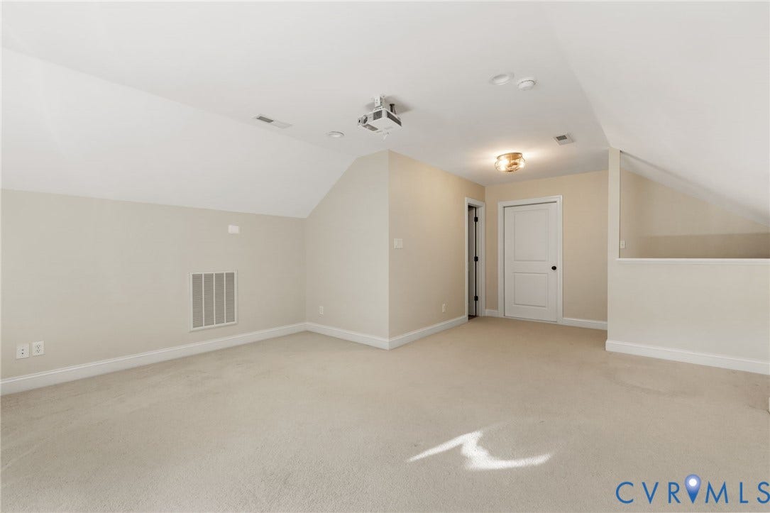 Carpeted room featuring a sloped ceiling, recessed lighting, a white panel door, and an attached ceiling-mounted projector