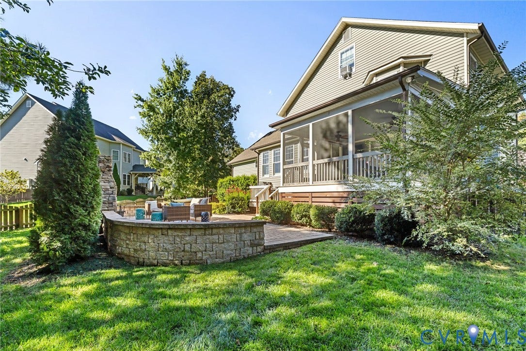 Screened porch, stone patio with built-in seating, stone fireplace, and manicured landscaping