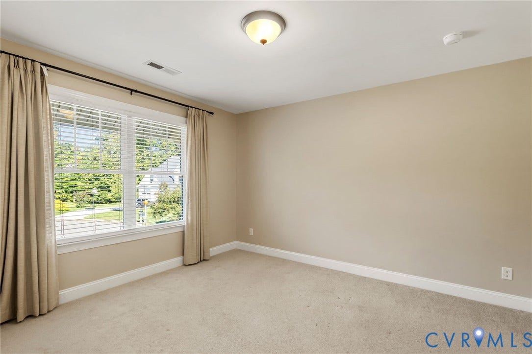 Wall-to-wall carpeting, large window with blinds, ceiling-mounted light fixture, and neutral wall tones