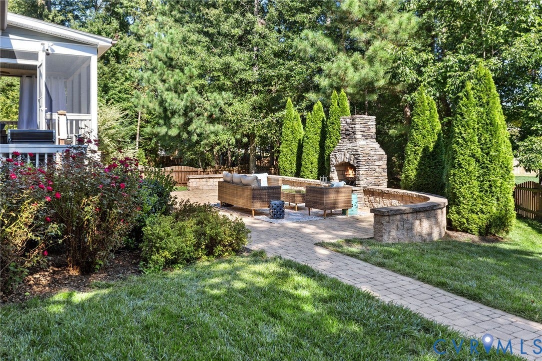 Expansive patio area featuring a stone fireplace, curved stone seating wall, and paver pathway