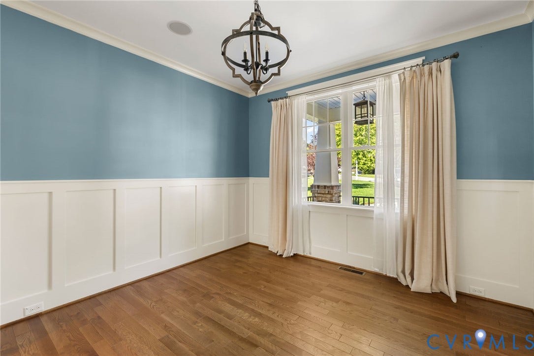 Hardwood flooring, crown molding, wainscoting, large window, and an ornamental chandelier