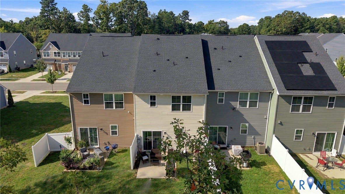Townhome exterior featuring individual patios, privacy fencing, and mature trees
