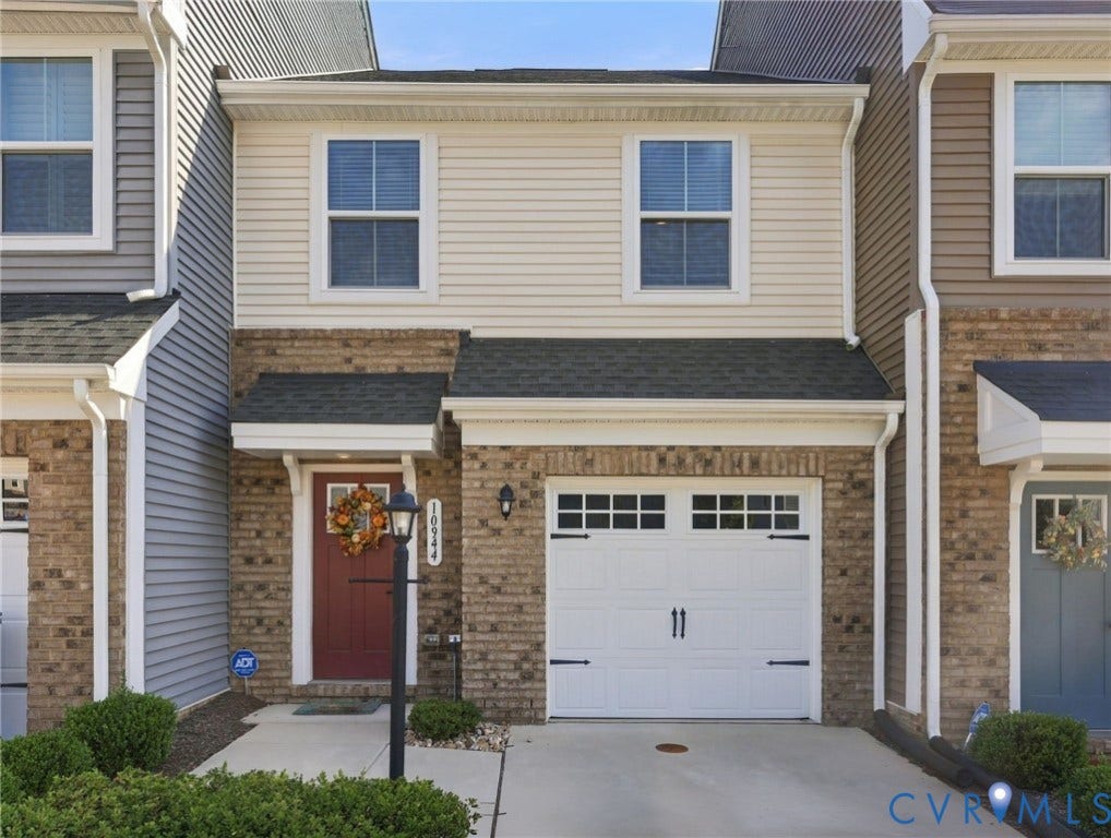 Brick and siding exterior with a dark red entry door