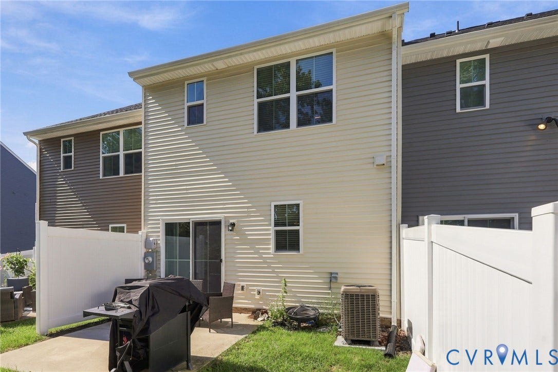 Private patio area with a sliding glass door, white vinyl fencing, and a manicured lawn