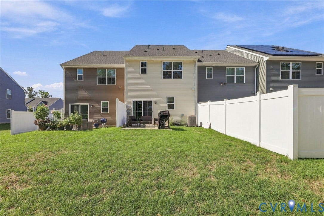 Expansive green lawn with a white privacy fence