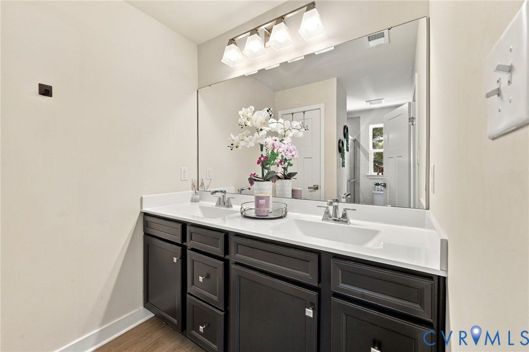 Dual vanity with dark wood-finish cabinetry, white countertops, and chrome fixtures