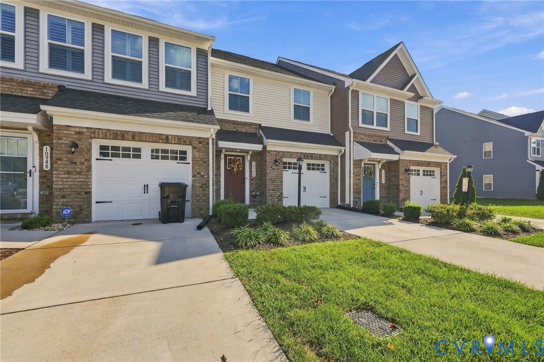 Brick and siding exterior featuring white garage doors with decorative hardware, an integrated single-car garage, and a concrete driveway