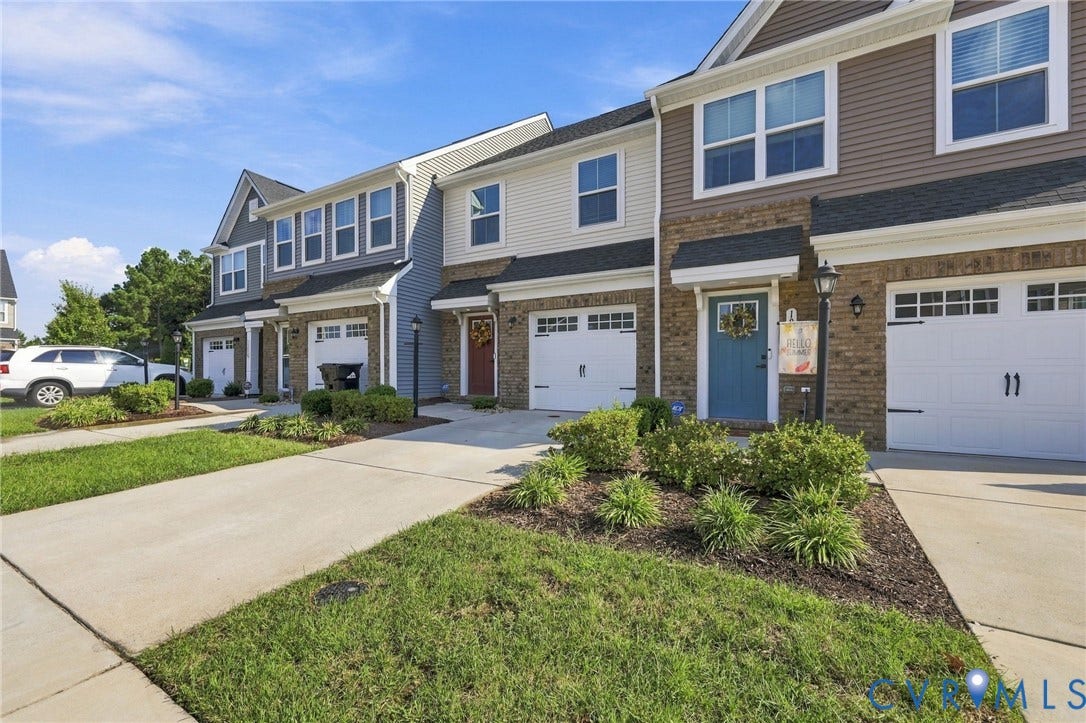 Multi-level townhome featuring brick and siding exterior, concrete driveway, and attached garage
