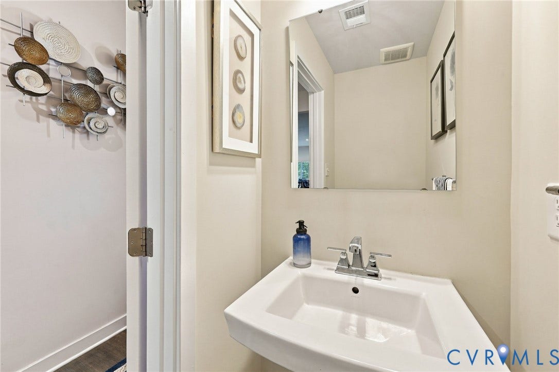 Pedestal sink with chrome fixtures and a rectangular mirror