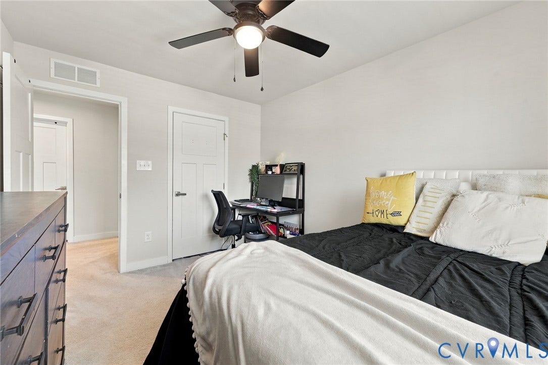 Neutral wall tones, carpeted flooring, and a ceiling fan with integrated lighting