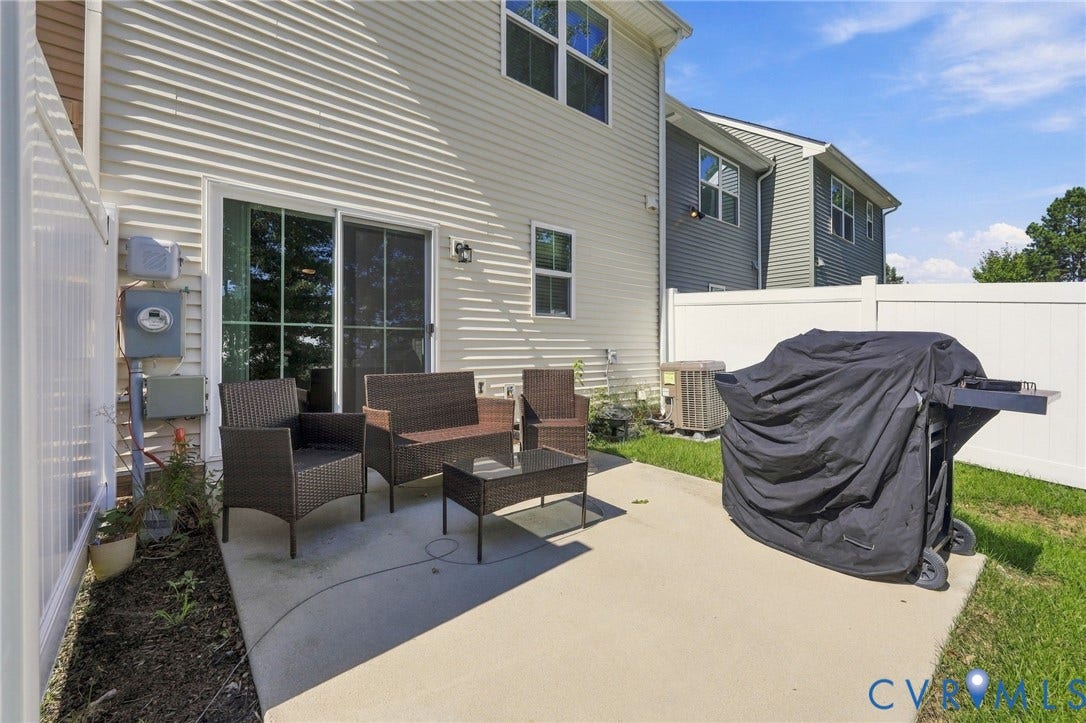Private rear concrete patio with vinyl siding exterior and white privacy fencing