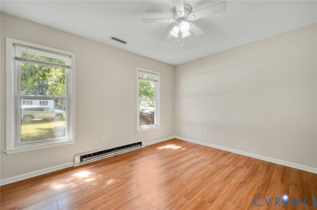 3530 Glisson Road, Richmond, VA 23237 Wood-finish flooring, two large windows, white ceiling fan with integrated lighting, neutral wall paint