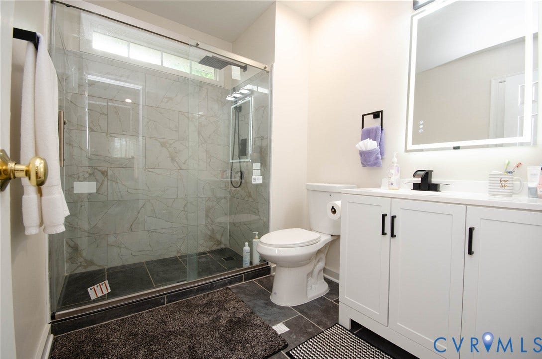 Glass-enclosed shower with tiled walls and a dark tiled floor
