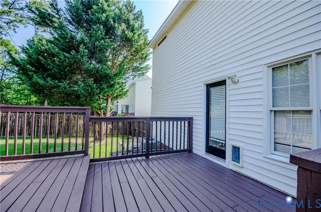 Expansive outdoor deck with wood-finish flooring and sturdy railings, offering direct access to the interior via a glass sliding door