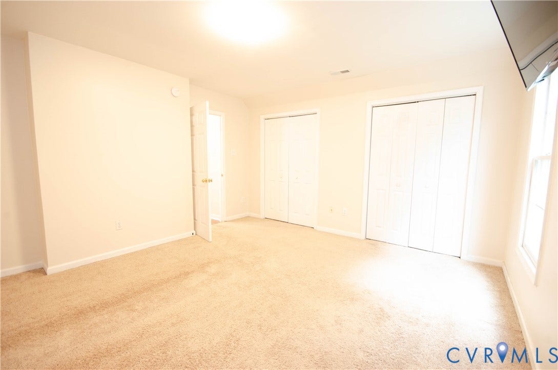 Neutral-toned carpeting, light-colored walls, recessed lighting, and two sets of bi-fold closet doors