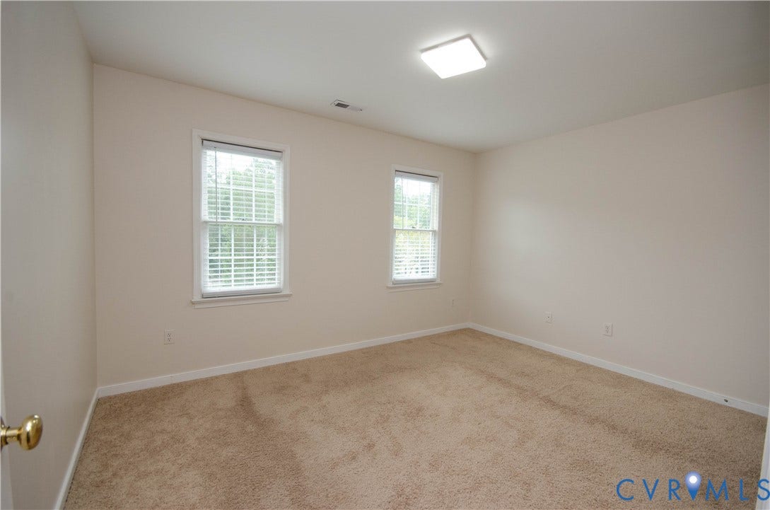 Neutral wall tones, two windows with blinds, recessed lighting, and carpeted flooring