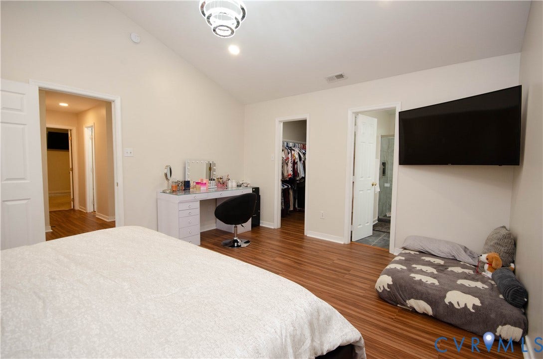 Vaulted ceiling with a contemporary flush mount light fixture, wood-finish flooring, and a wall-mounted television