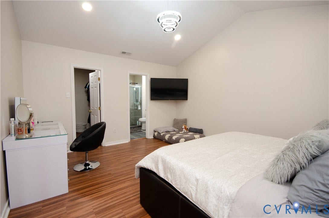 Vaulted ceiling, recessed lighting, wood-finish flooring, built-in closet, and an attached bathroom with a glass-enclosed shower