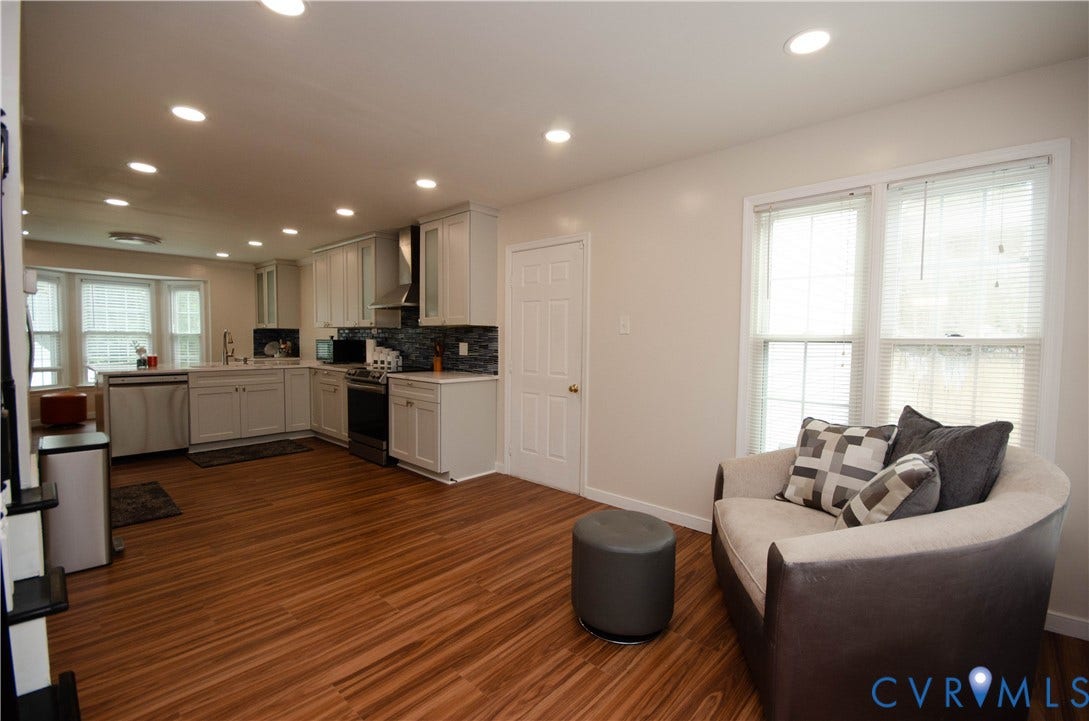 Recessed lighting illuminates the open-concept living space with wood-finish flooring