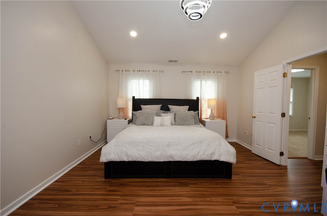 Vaulted ceiling with recessed lighting, wood-finish flooring, and a contemporary ceiling fixture