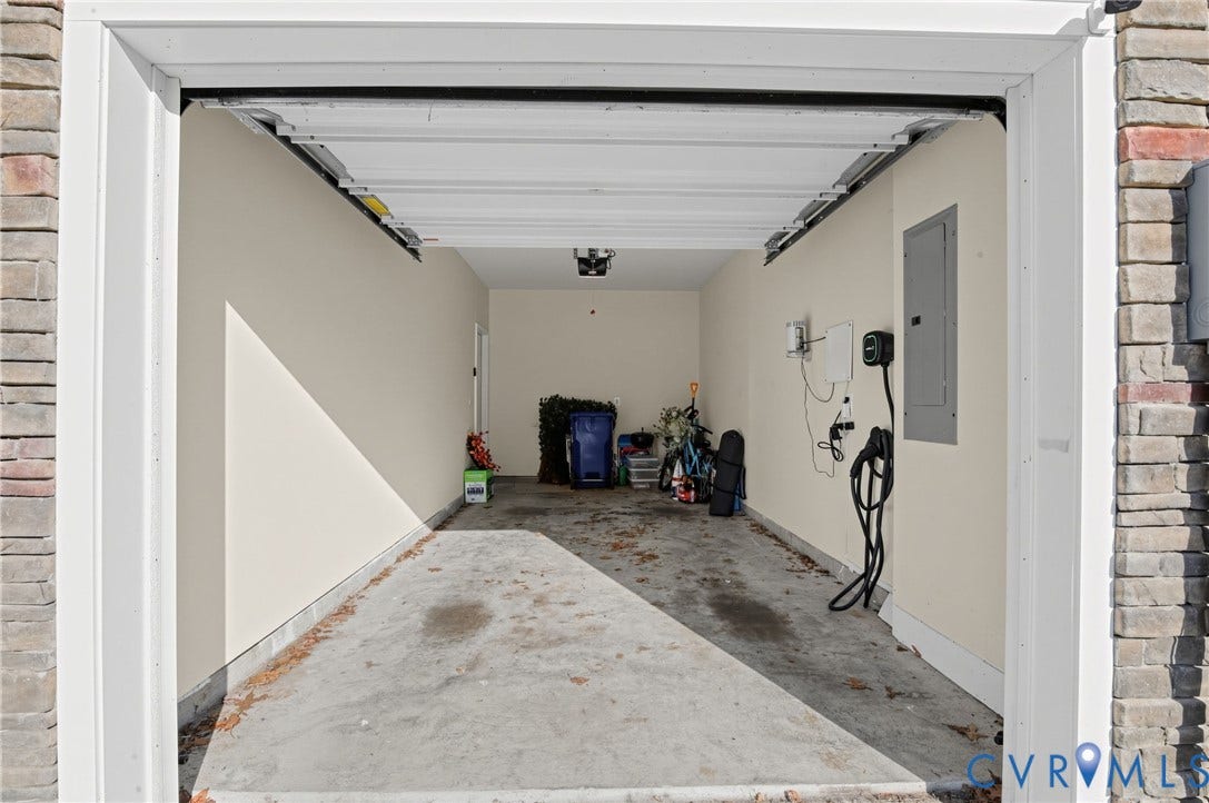 Attached garage with concrete flooring, finished interior walls, and an integrated electrical panel