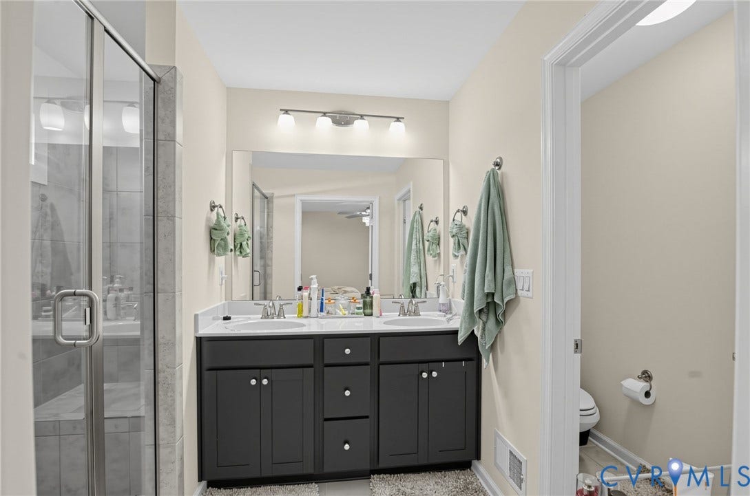 Dual vanity with undermount sinks, a large mirror, and a glass-enclosed shower with a built-in bench and tiled walls