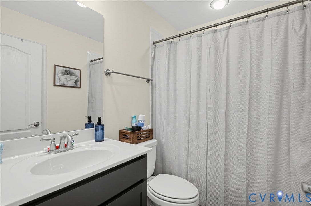 Bathroom with a white toilet, chrome fixtures, built-in vanity with dark cabinetry, and an overhead light