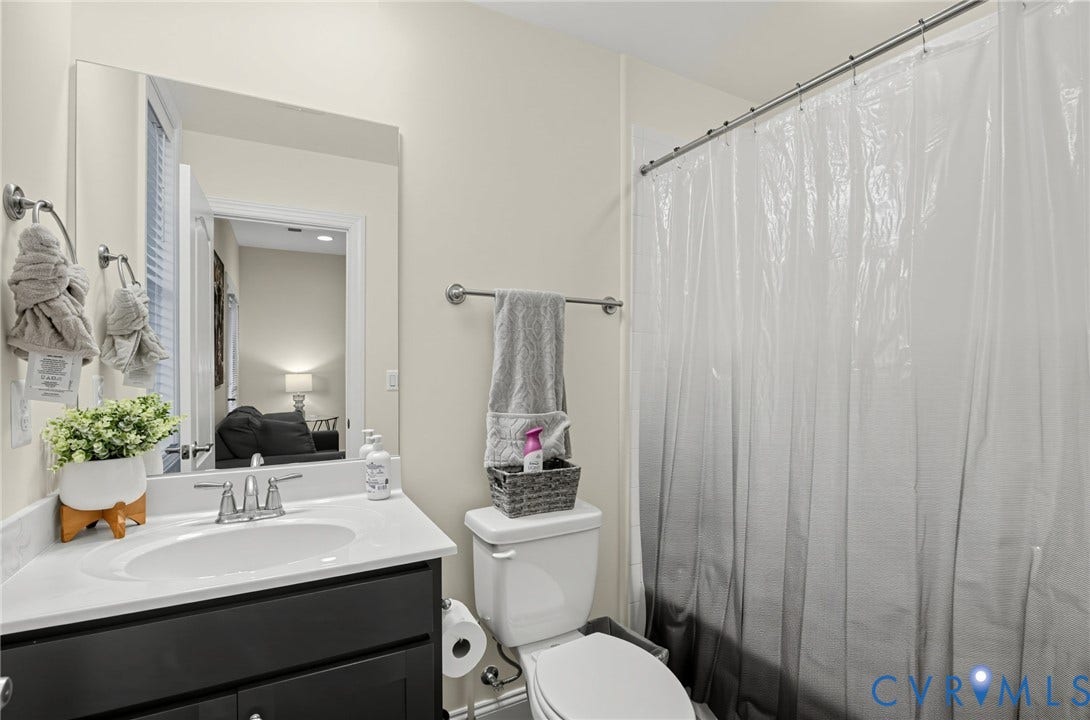 Bathroom featuring a dark wood-finish vanity with a white countertop, an undermount sink, a wall-mounted mirror, and a shower with a privacy curtain