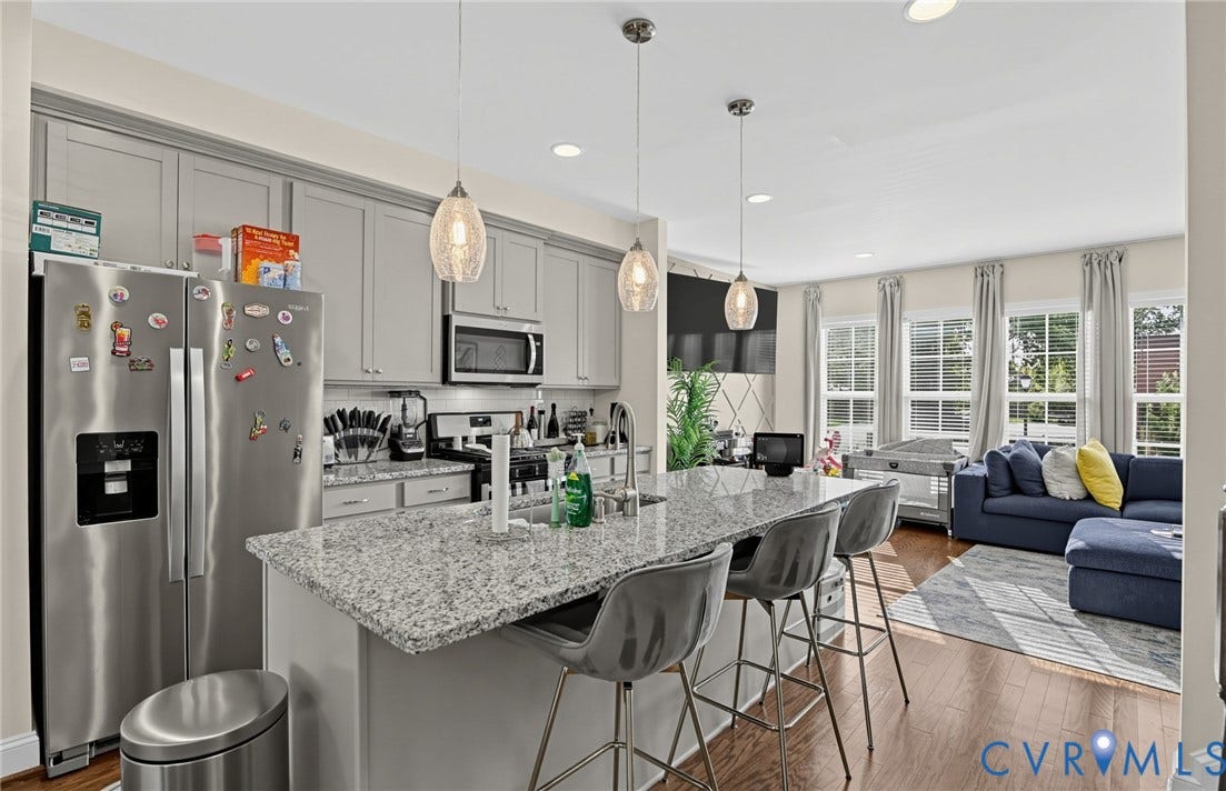 Kitchen featuring stainless steel appliances, light gray cabinetry, and a spacious island with a stone countertop