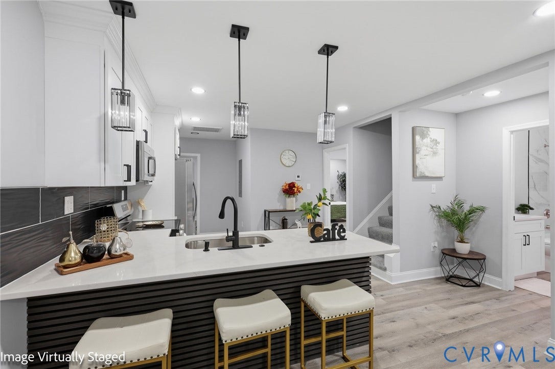 510 N Carolina Avenue, Petersburg, VA 23803 Kitchen island with a white countertop and integrated sink, pendant lighting, white cabinetry, wood-finish flooring, and a dark tile backsplash