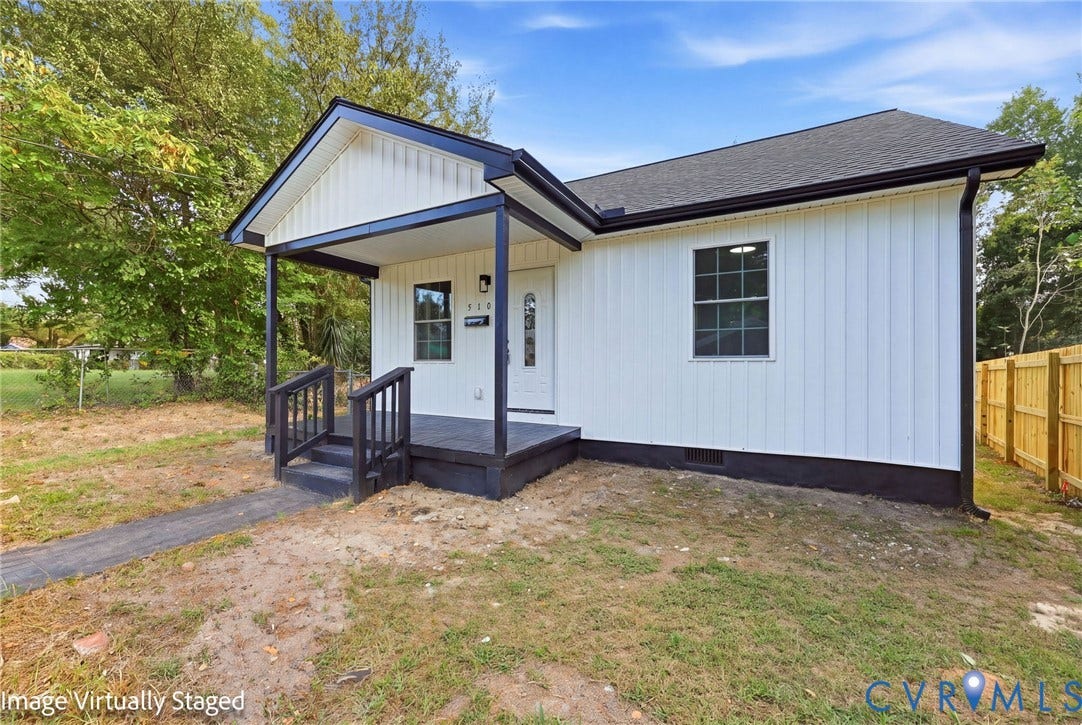 510 N Carolina Avenue, Petersburg, VA 23803 White vertical siding exterior, covered porch with dark railing, dark trim, dark shingled roof, and a wooden fence