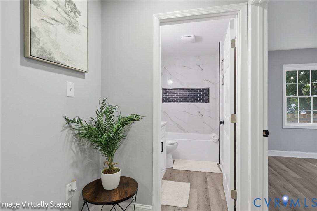 510 N Carolina Avenue, Petersburg, VA 23803 Bathroom featuring full-height marble-style tile surround with a tiled shower niche, white tub, and wood-finish flooring