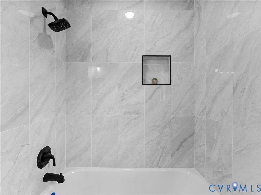 7361 Creekridge Road, Henrico, VA 23231 Bathtub with a matte black shower head, matte black faucet, and tiled surround featuring a recessed niche